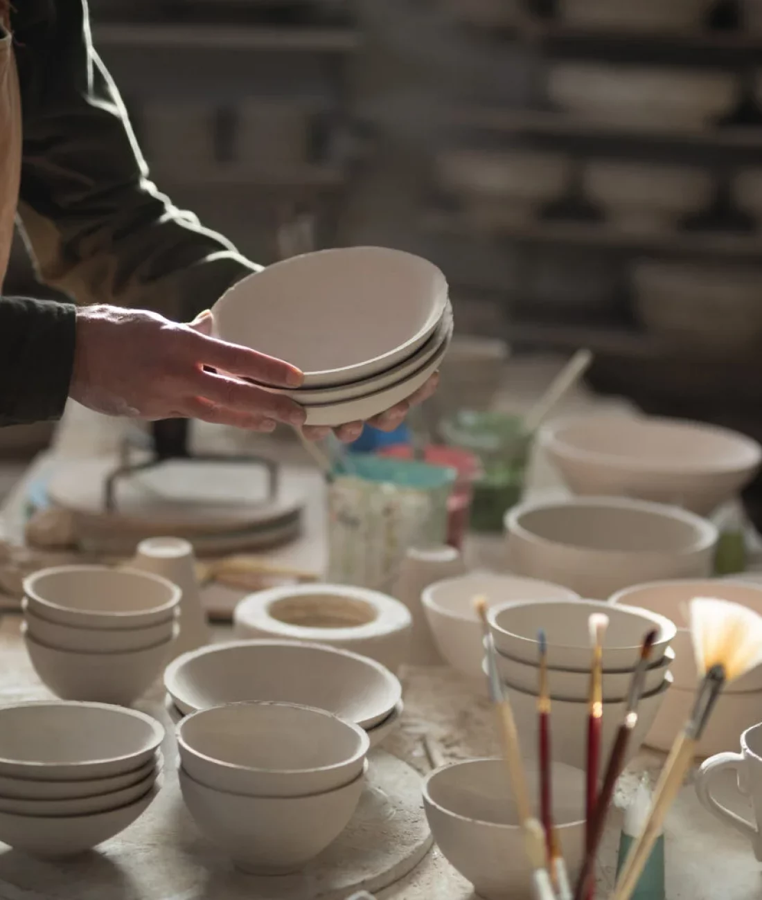 mid section of male potter holding bowls utc x